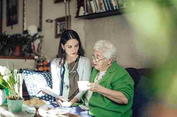 Begeleider kijkt met oudere vrouw naar administratie 