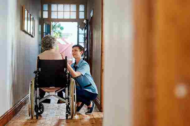 Zorgverlener in de langdurige zorg praat met bejaarde vrouw in rolstoel