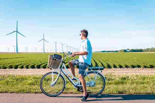 Man rijdt op fiets door Utrechts landschap met windmolens